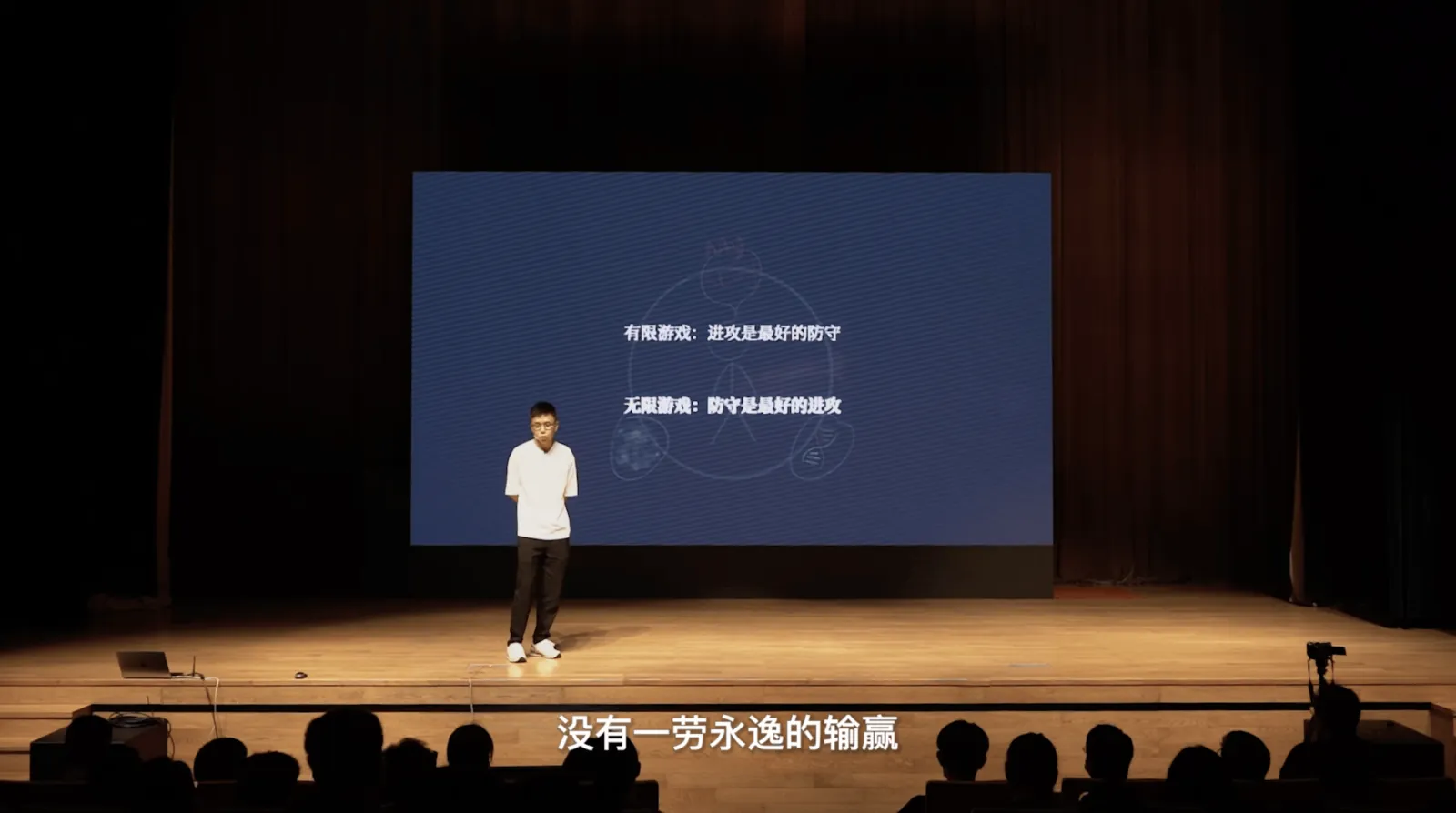 剧场舞台上,大萤幕写着:有限游戏,进攻是最好的防守;无限游戏,防守是最好的进攻